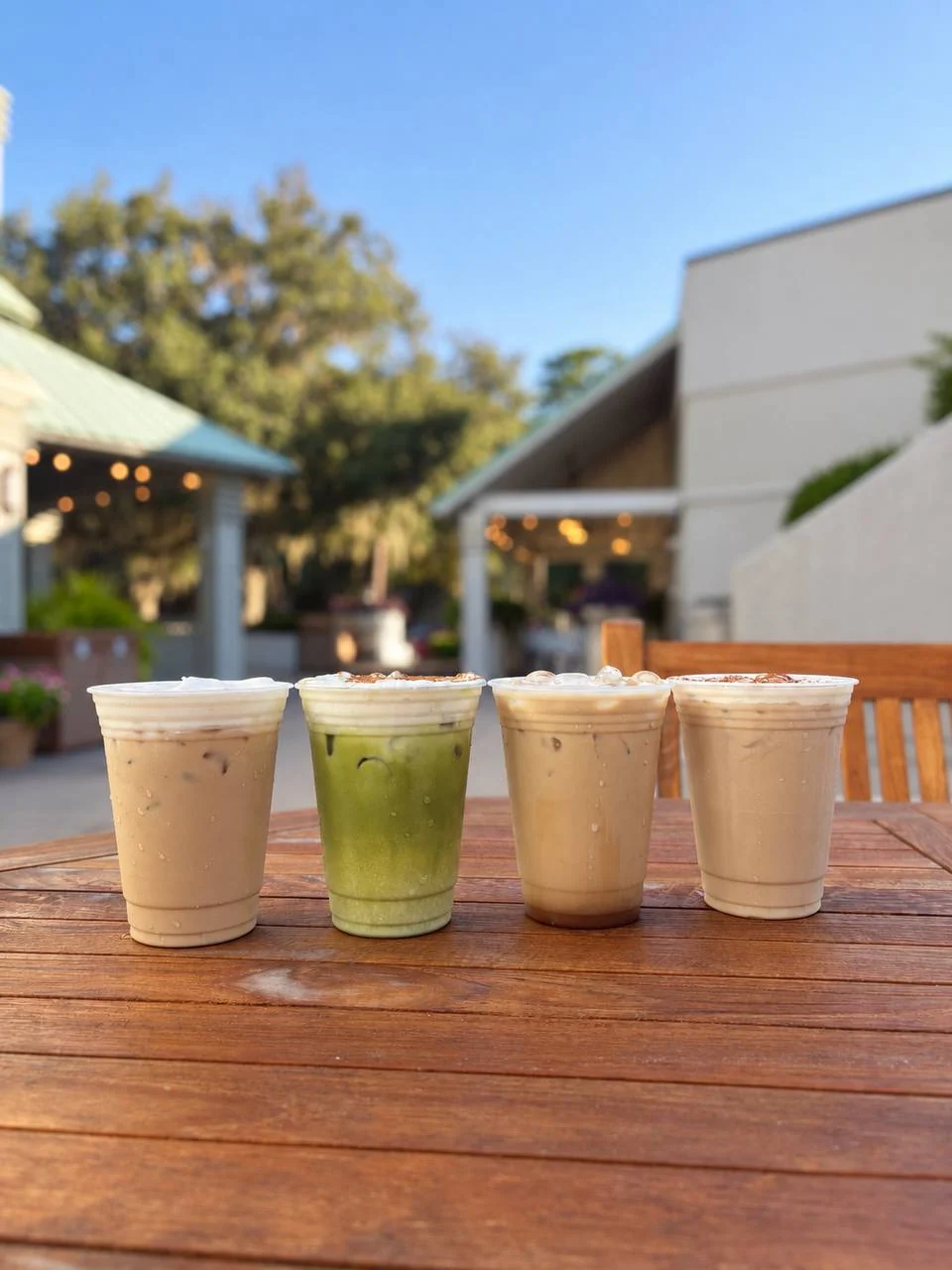 Four iced fall drinks, including a matcha latte, on a wooden patio table at The Shops at Sea Pines Center